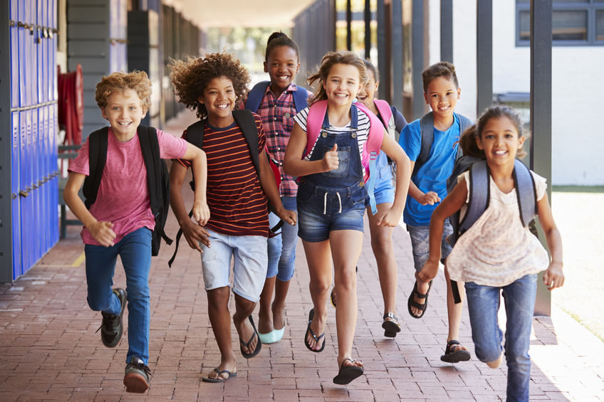 School kids running in elementary school hallway, front view group of students