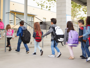 Grade school children getting off the bus and walking into school