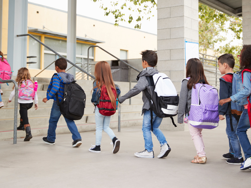 Grade school children getting off the bus and walking into school