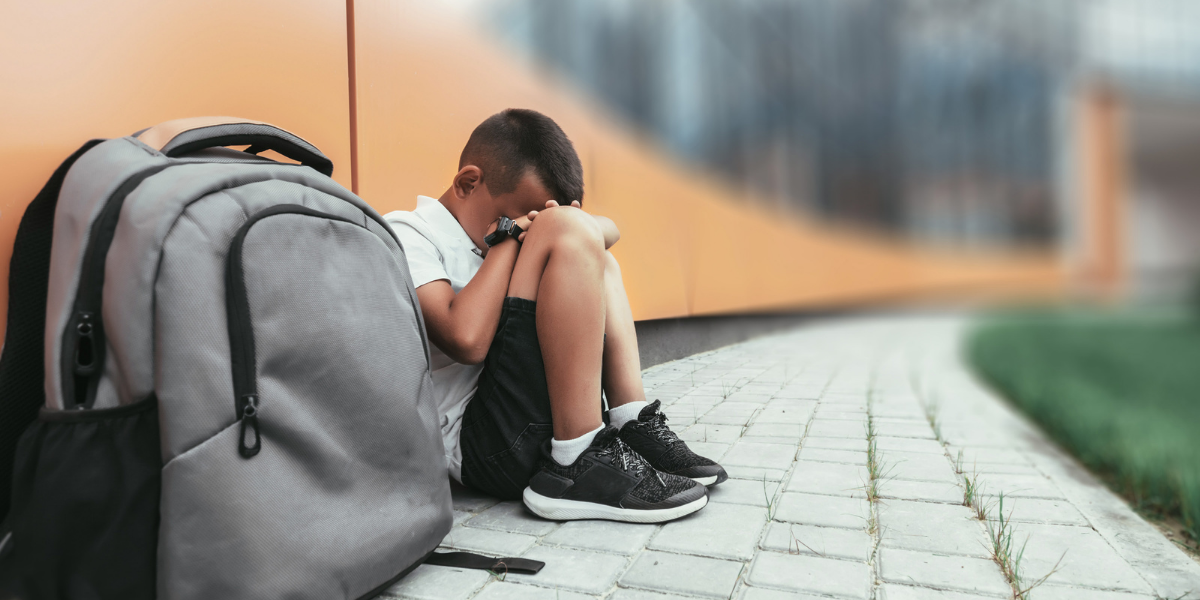 sad kid near bookbag