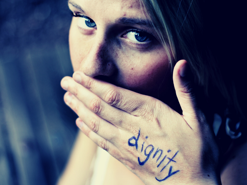 hand covering girl's mouth with word dignity written on it