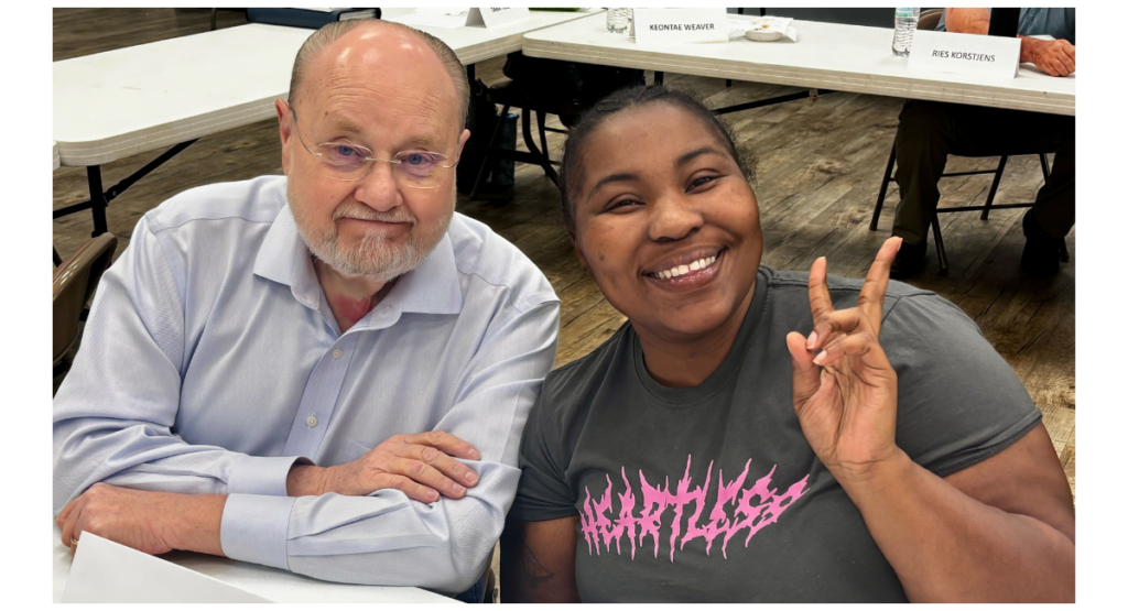 Ayonia, at right, smiles for the camera. She is seated next to her program Champion, Fred Blackwell, at left.